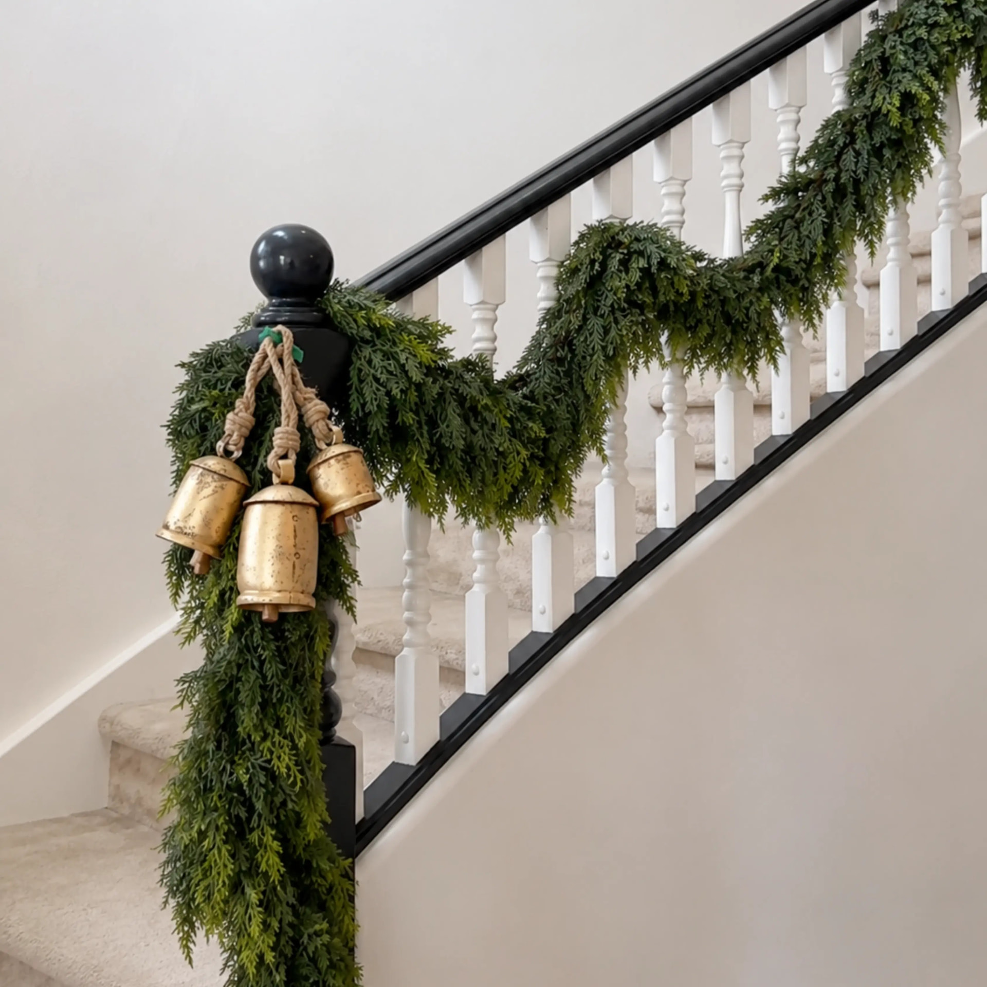 Cedar garland swagged along a white staircase banister with gold bells